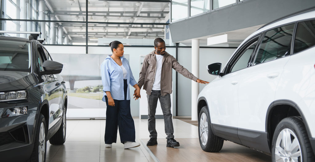 Couple comparant deux modèles de véhicules dans une concession automobile Peugeot